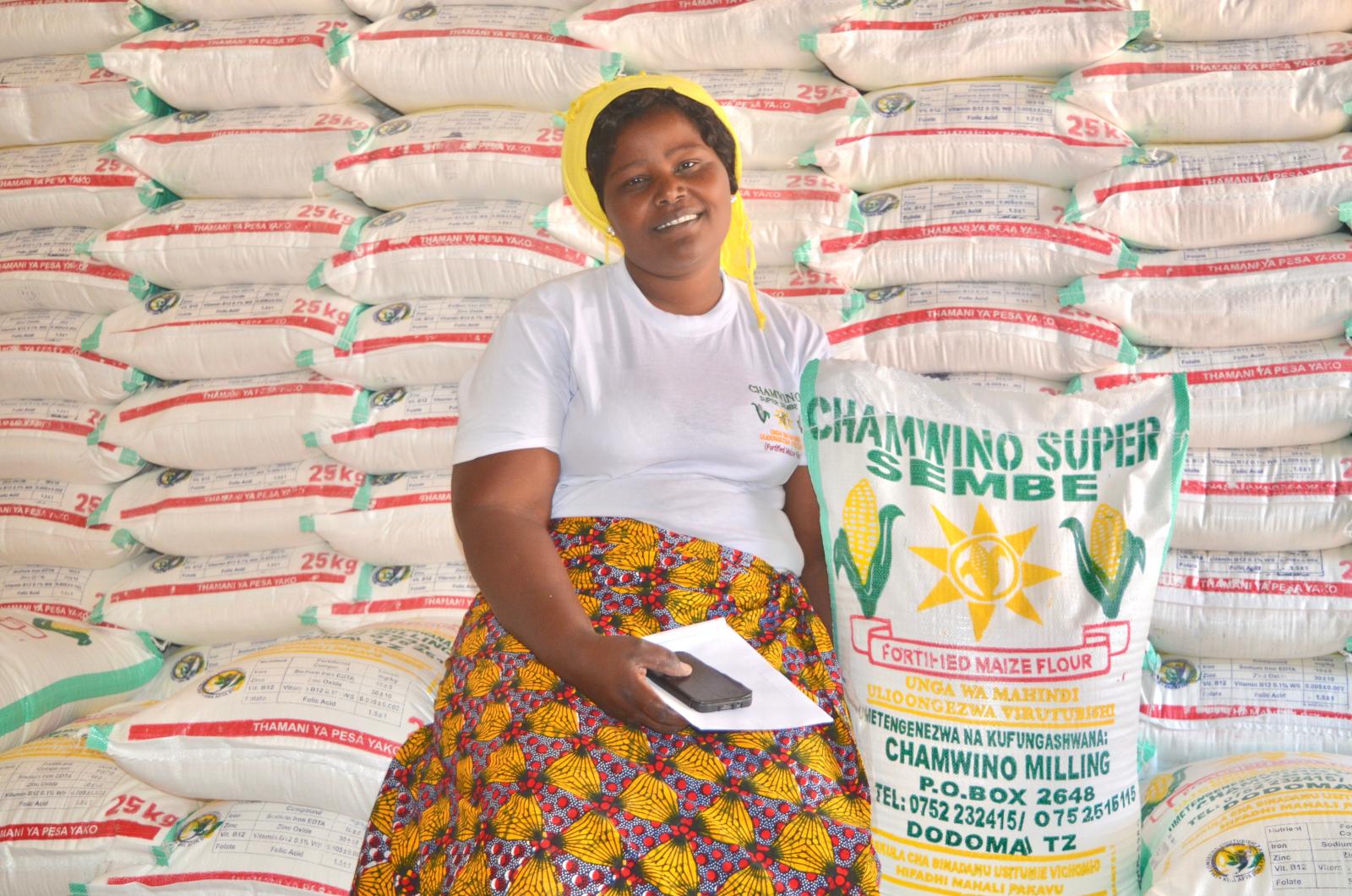Woman posing with many sacks of maize flour