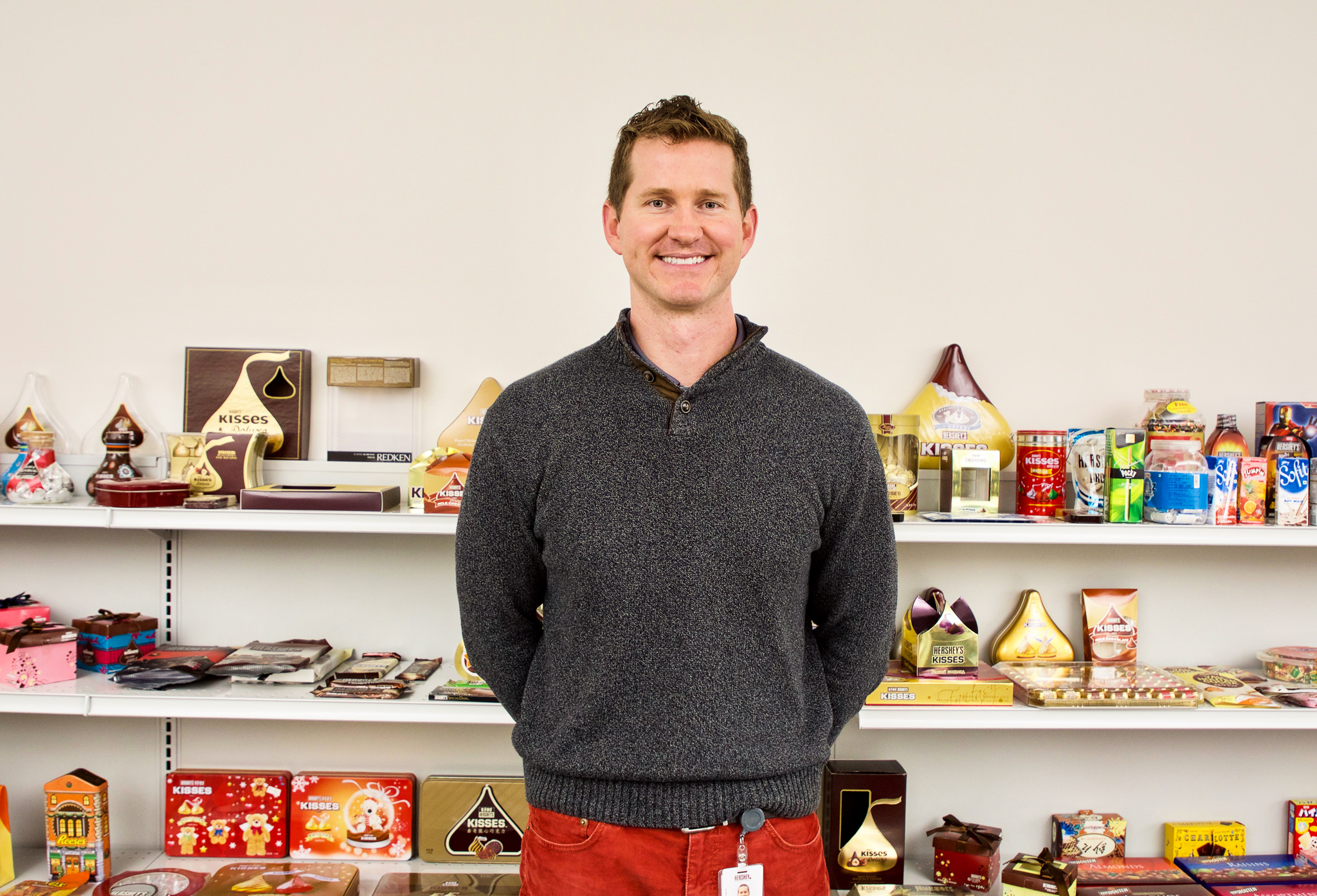 A person standing in front of shelves of chocolates.
