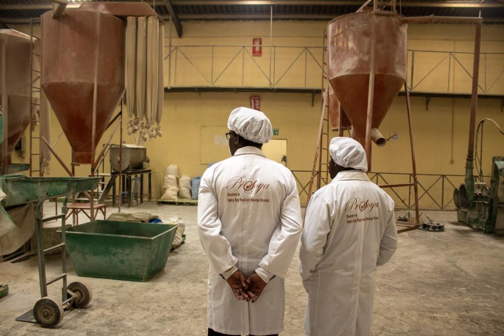 Prosoya CEO and TechnoServe staff standing inside processing facility 